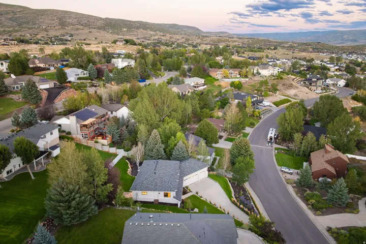 Expansive neighborhood with established trees, paved roads, and distant hills