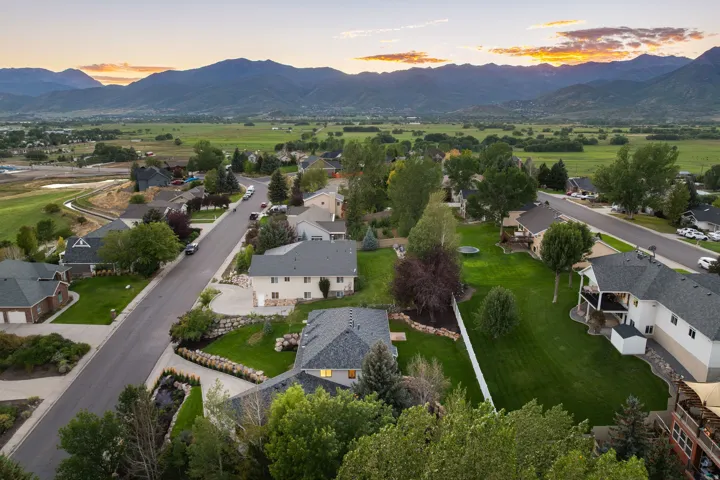 Neighborhood setting with distant mountain range, expansive green fields, and a paved street