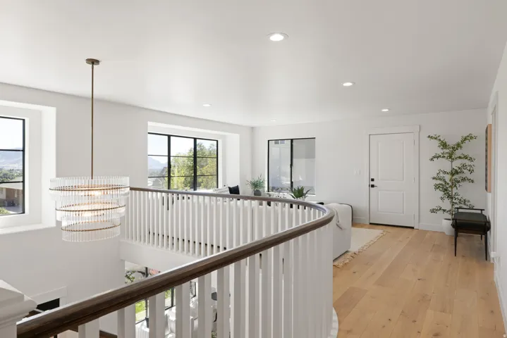 Open upper-level landing with light wood-finish flooring, white walls, and recessed lighting