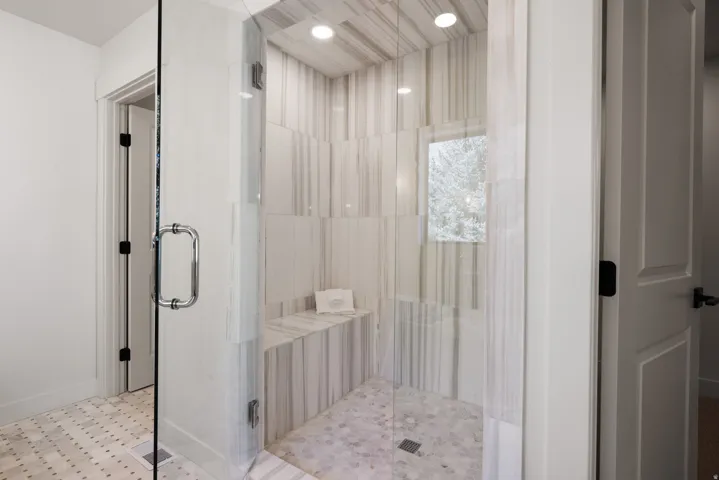 Glass-enclosed shower with a built-in bench, hexagonal tile flooring, and integrated ceiling lighting