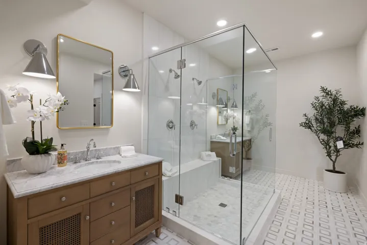 Glass-enclosed shower with multiple showerheads and a built-in bench