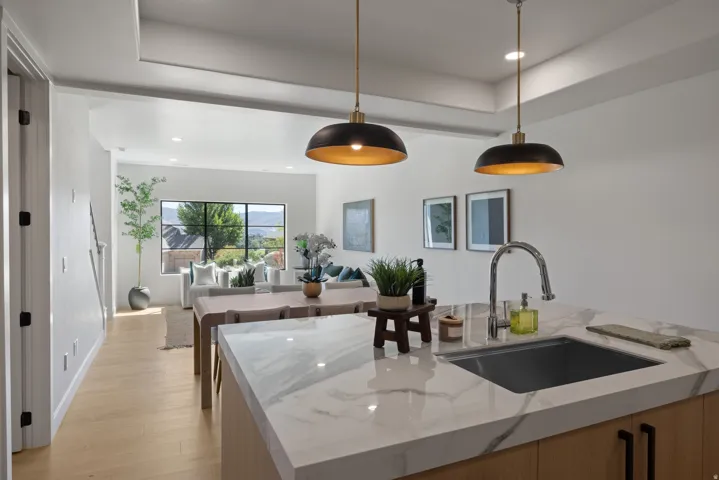 Kitchen island with a waterfall edge countertop, undermount sink, and gooseneck faucet