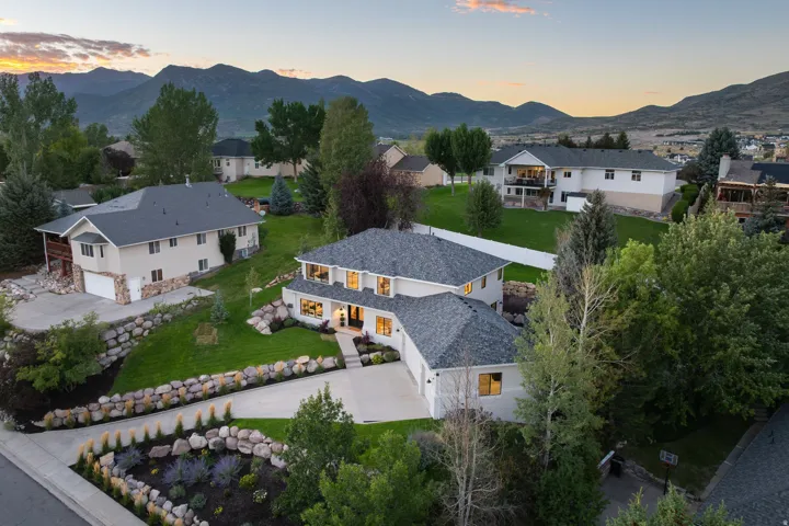 Expansive mountain scenery, tiered landscaping, stone retaining walls, mature trees, and a paved driveway