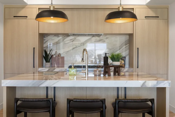 Kitchen island featuring a waterfall-edge countertop, undermount sink, and integrated bar seating