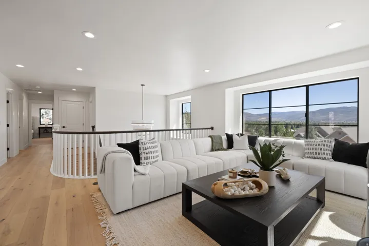 Wood-finish flooring, recessed lighting, and a white balustrade with a dark wood-finish handrail