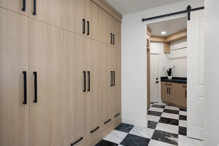 Custom built-in cabinetry with black hardware, barn door entry with black hardware, black and white checkerboard flooring, recessed lighting, and built-in shelving