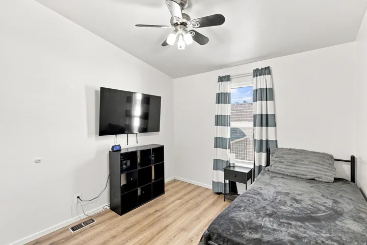 Wood-finish flooring, ceiling fan with integrated lighting, and a window with natural light