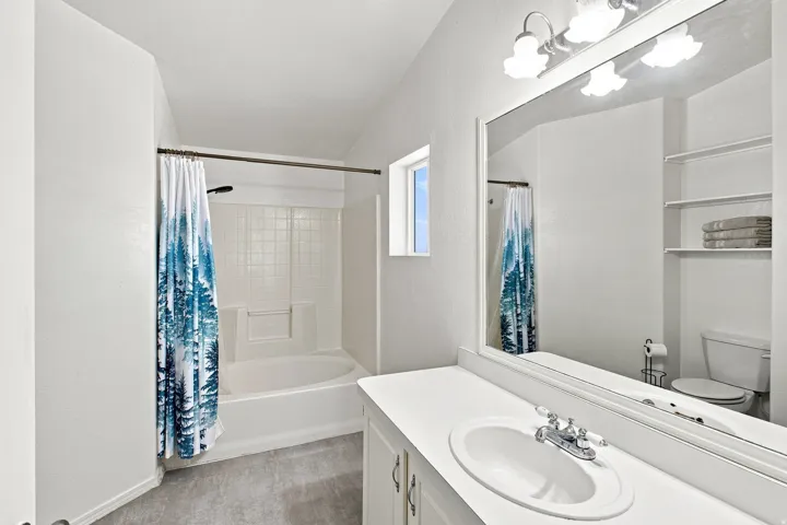 White vanity with integrated sink, chrome faucet, and a large wall-mounted mirror