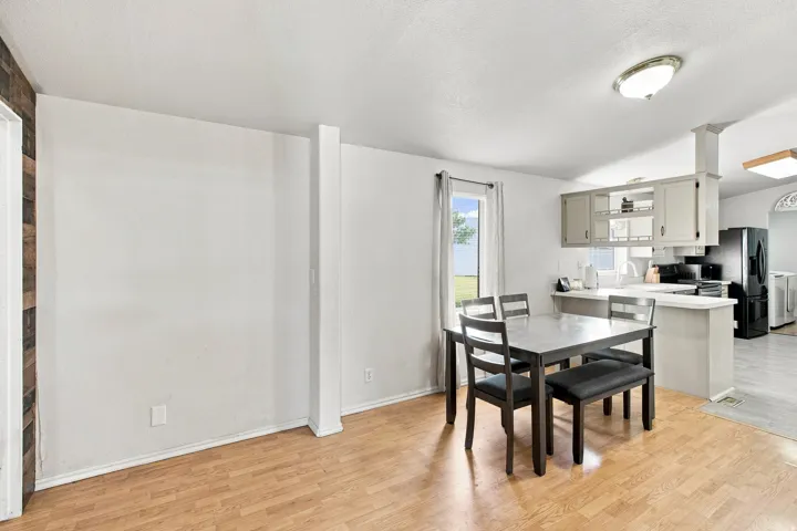 Wood-finish flooring throughout, white walls, recessed kitchen cabinetry, kitchen counter space, and an overhead light fixture