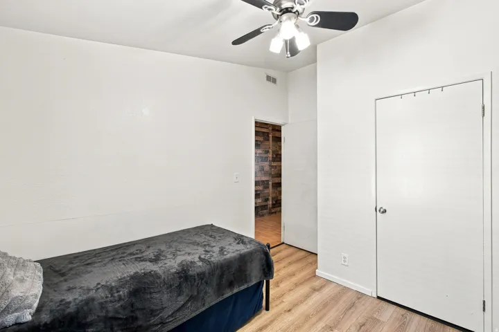 Wood-finish flooring, white walls, and a ceiling fan with integrated lighting
