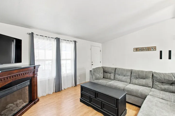 Living area featuring wood-finish flooring, multiple windows, a decorative fireplace, and a white entry door