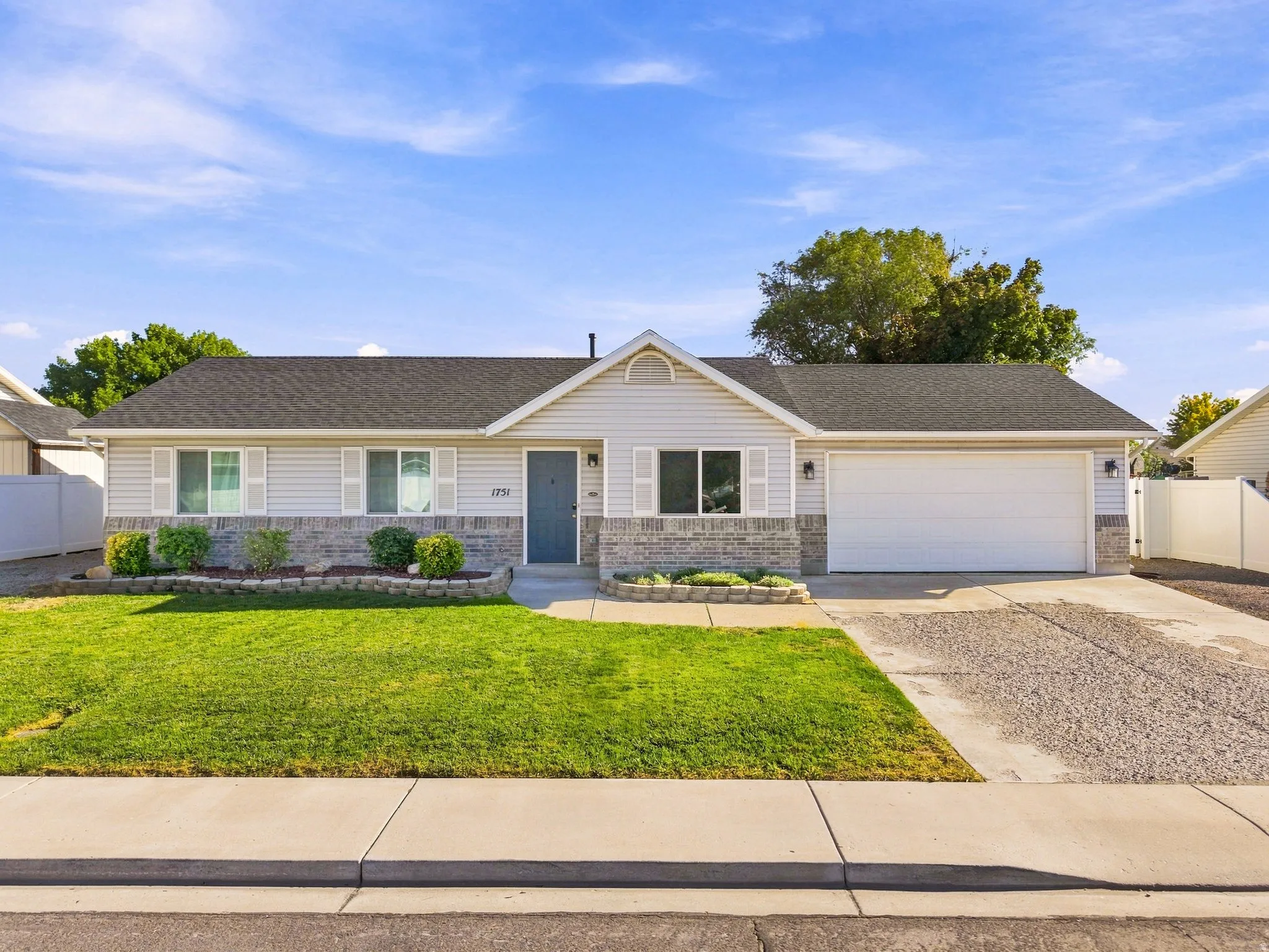 Single-story residence featuring siding and stone veneer, an attached garage, a front lawn, and a paved driveway