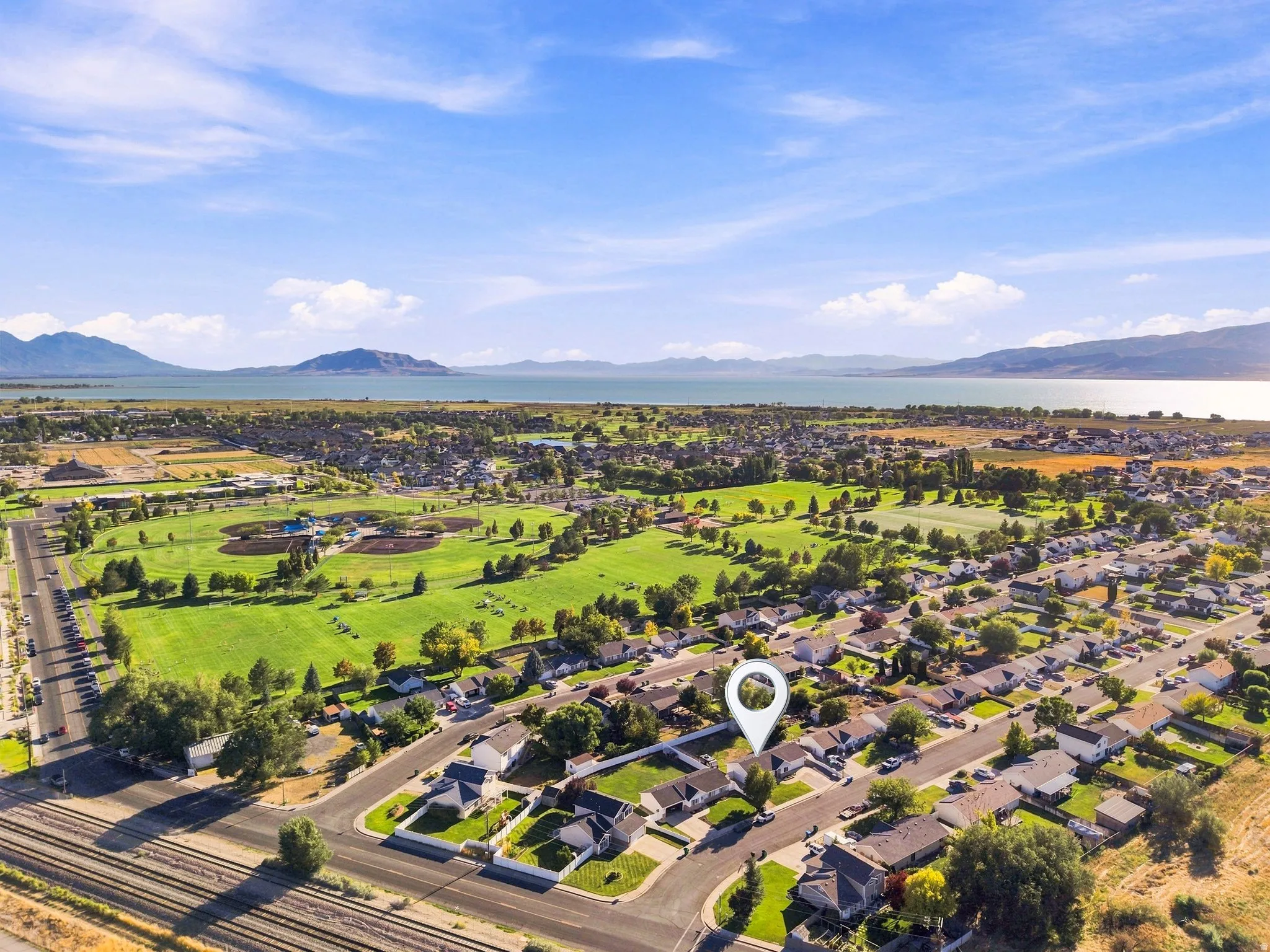 Expansive water body, distant mountains, green recreational fields, and residential streets