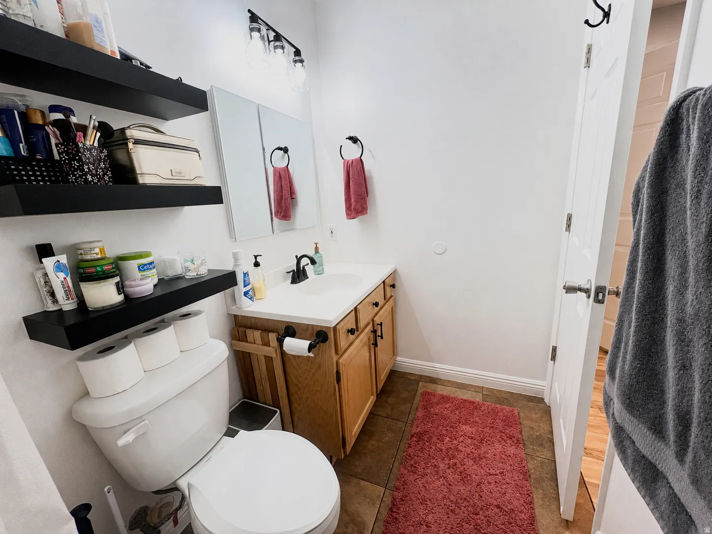 White vanity with integrated sink, black hardware, and wall-mounted light fixture