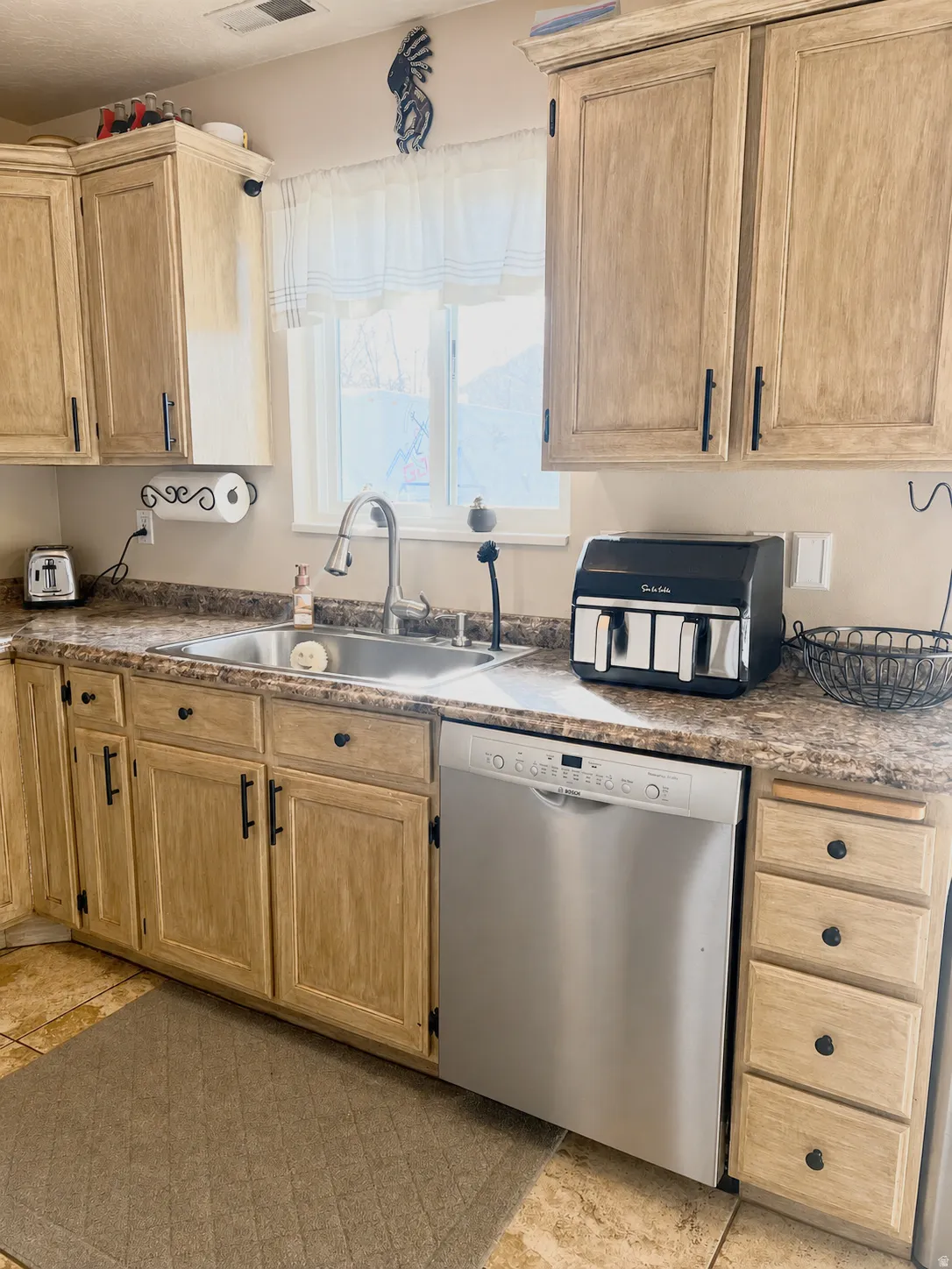 Light-toned cabinetry with black hardware, complementing countertop, stainless steel sink, and stainless steel dishwasher