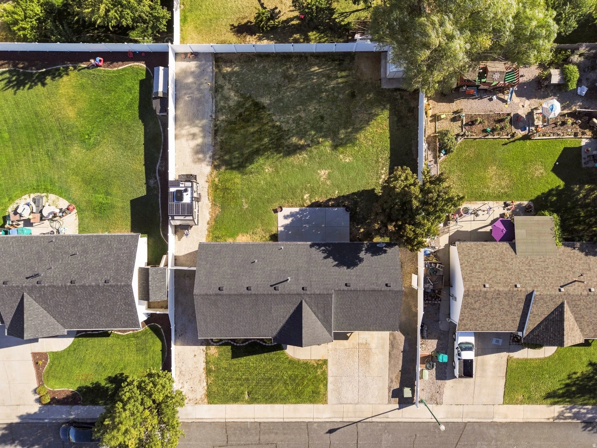 Property featuring a dark shingle roof, a concrete driveway, and a front lawn with mature trees