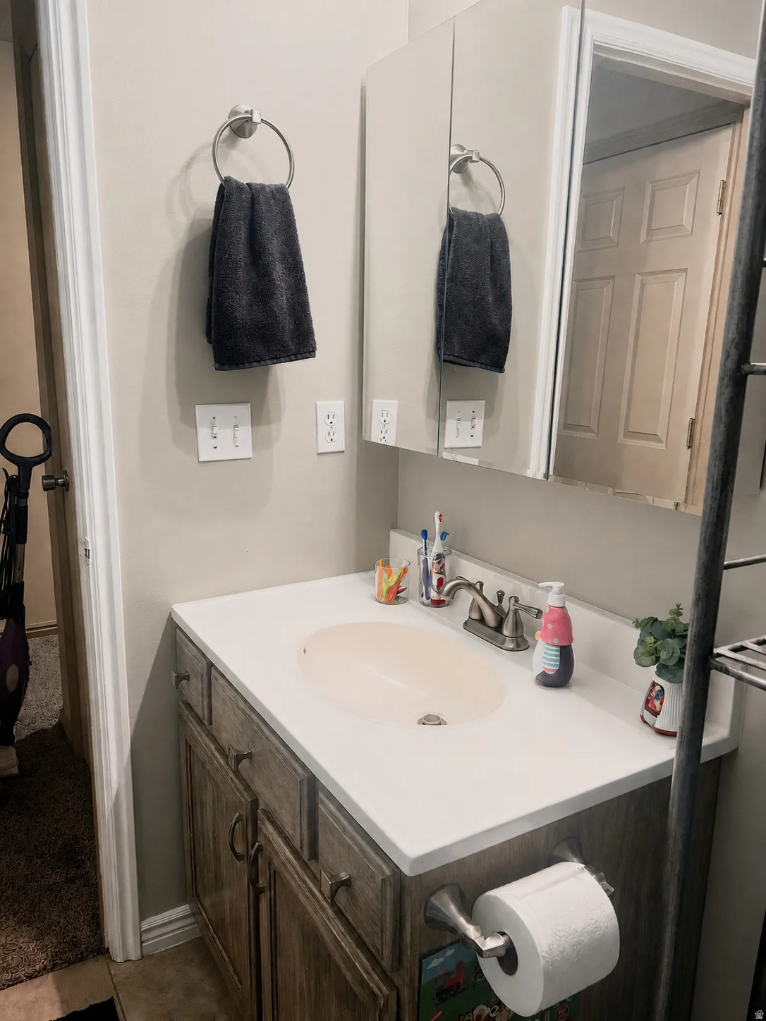 Bathroom vanity with a built-in sink, brushed nickel faucet, and wood-finish cabinetry with dark hardware