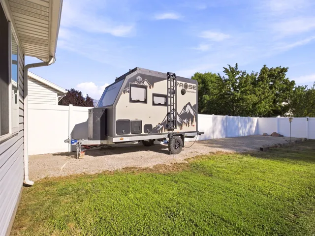 Gravel parking area with a white vinyl fence and a lawn section