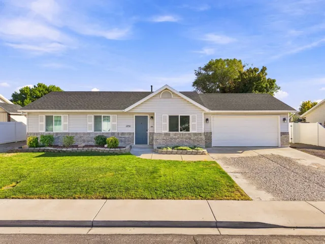Single-story residence featuring siding and stone veneer, an attached garage, a front lawn, and a paved driveway