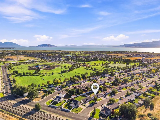 Expansive water body, distant mountains, green recreational fields, and residential streets