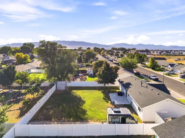 Expansive rear yard featuring a manicured lawn, full privacy fencing, and a concrete patio