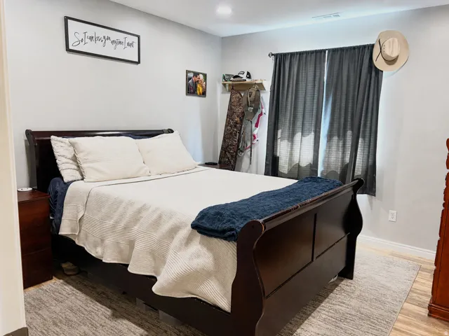 Recessed lighting, wood-finish flooring, and a window with dark drapery
