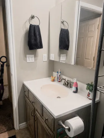 Bathroom vanity with a built-in sink, brushed nickel faucet, and wood-finish cabinetry with dark hardware