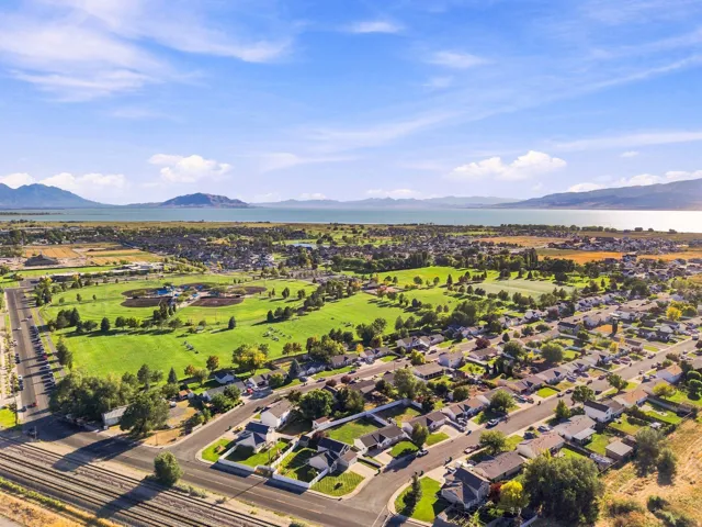 Expansive neighborhood featuring residential properties, recreational green spaces, and a prominent body of water in the background