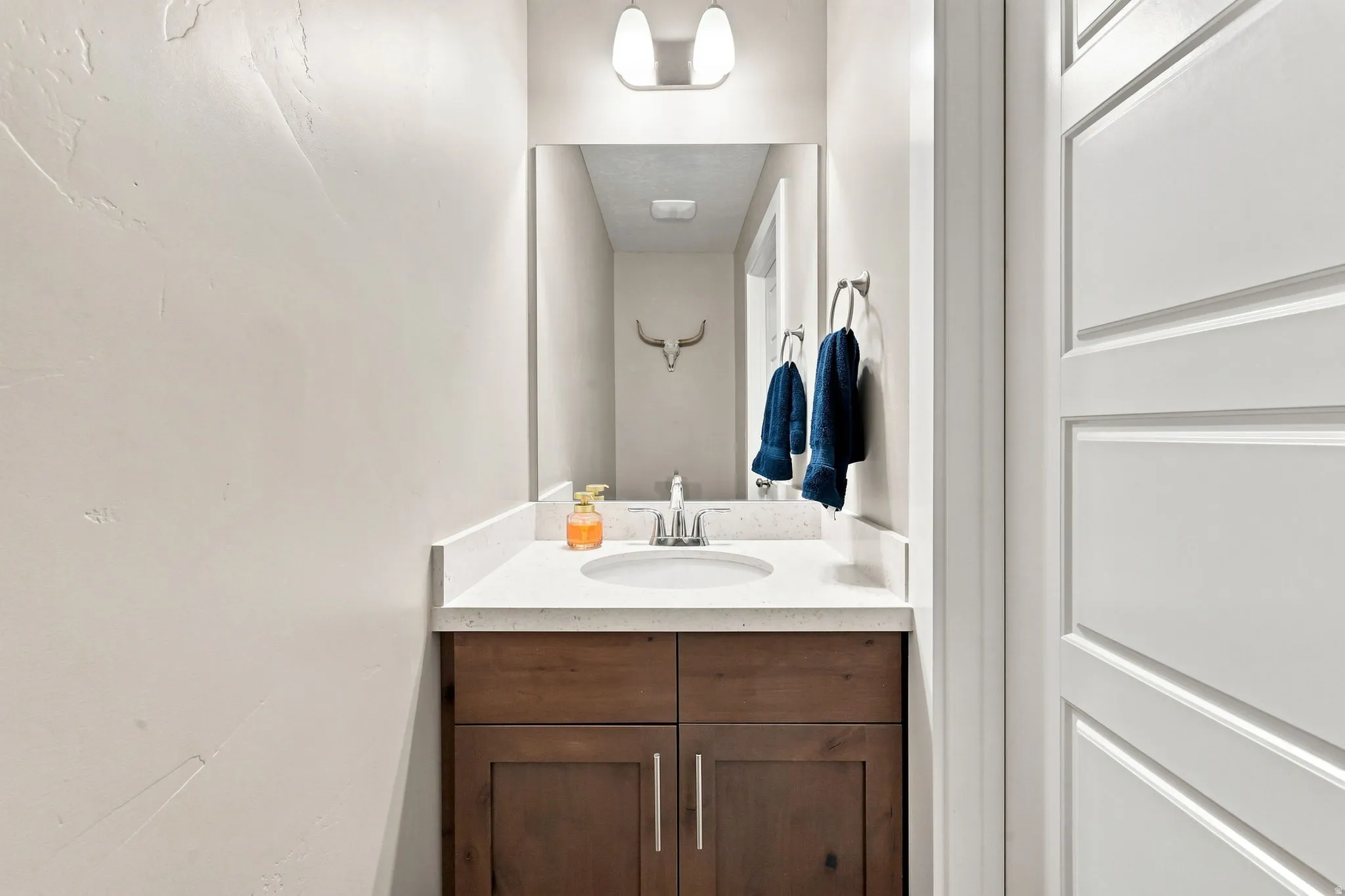 Vanity with a built-in sink, stainless steel faucet, and light-toned countertop