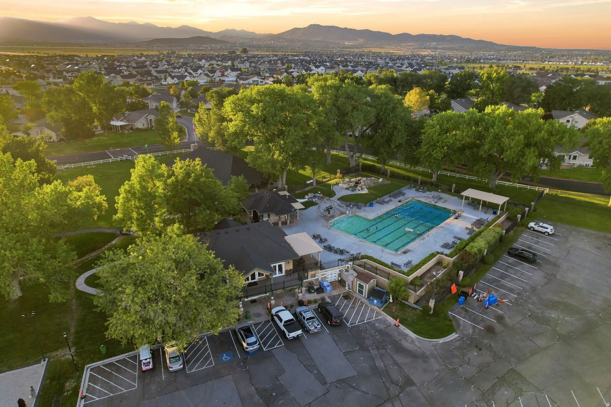 Large community pool with dedicated lap lanes and sun shelf, surrounded by a paved patio and shaded lounging areas