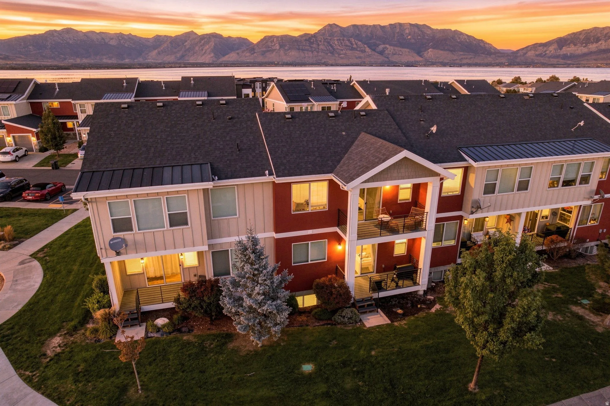 Townhome exterior featuring board and batten siding, multiple balconies with metal railings, a paved walkway, and a landscaped lawn