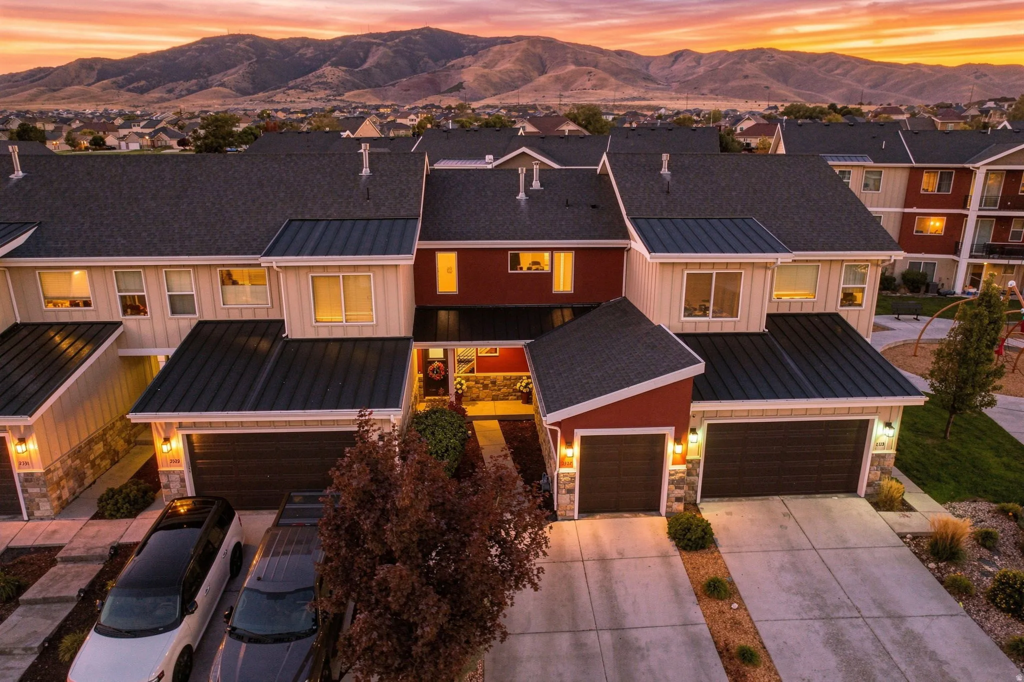 Townhome exterior featuring multiple garages, a combination of shingle and metal roofing, and stone accents