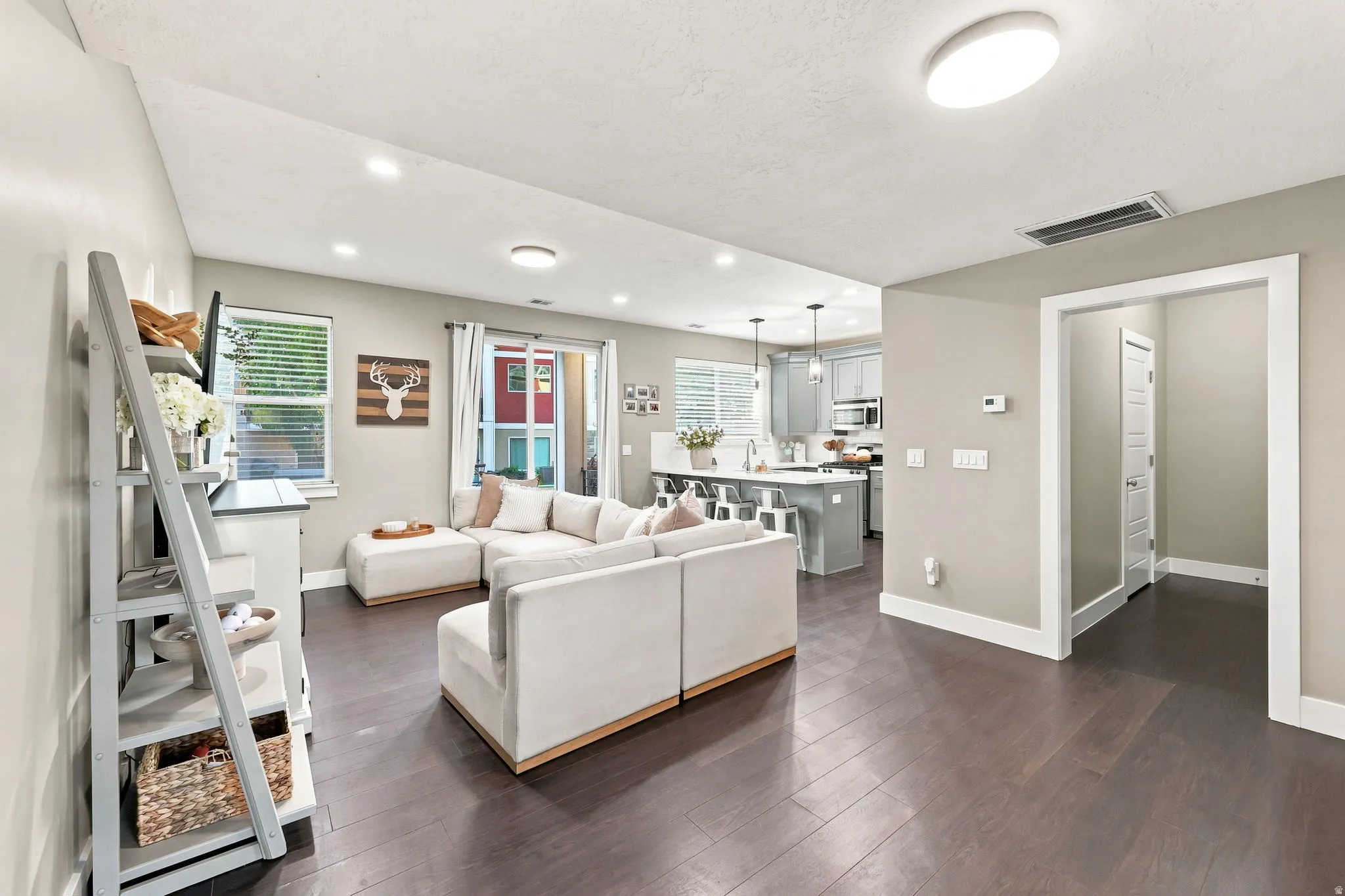 Open concept living area with wood-finish flooring, recessed lighting, and a sliding glass door