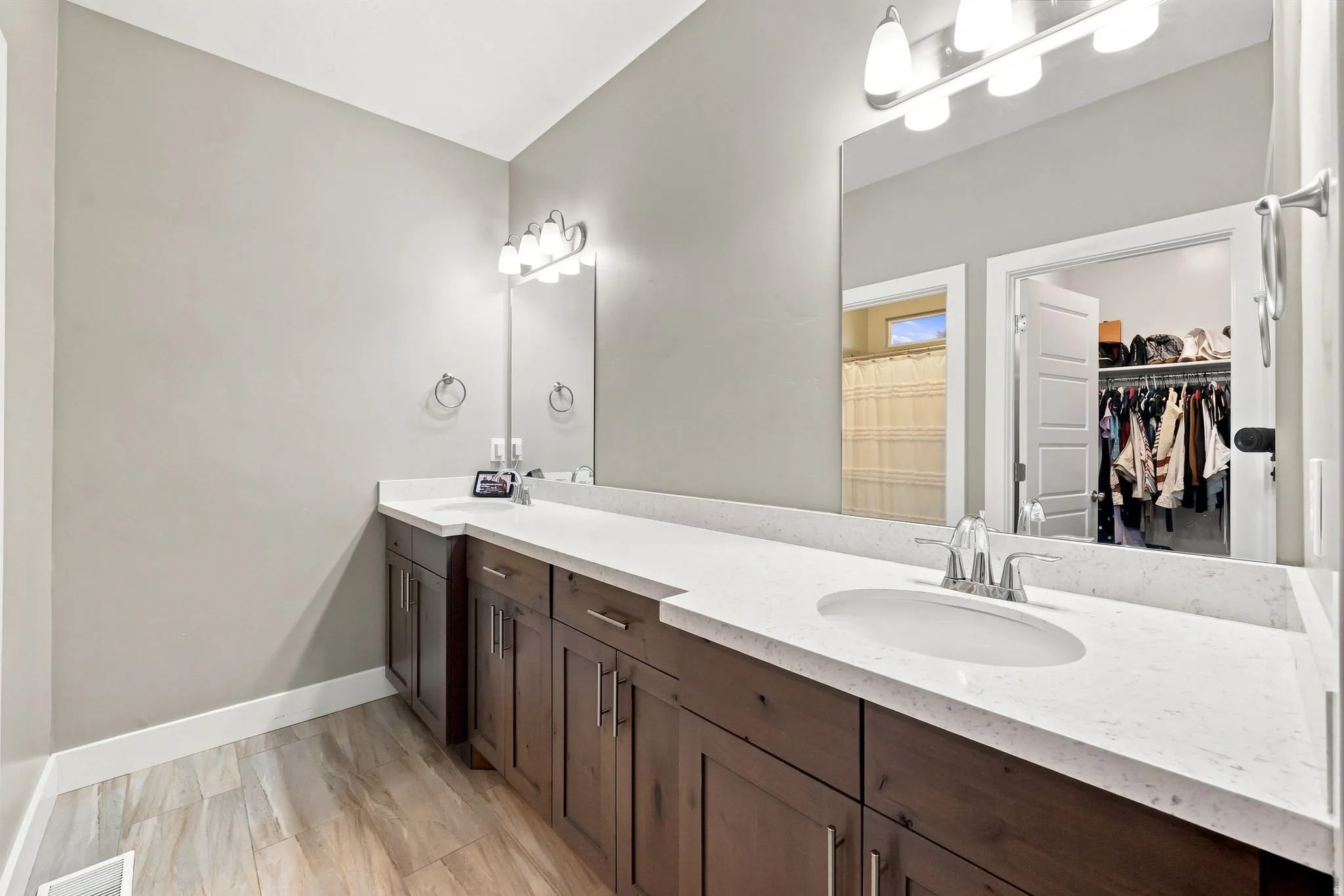 Dual vanity with white countertops, undermount sinks, and wood-finish cabinetry