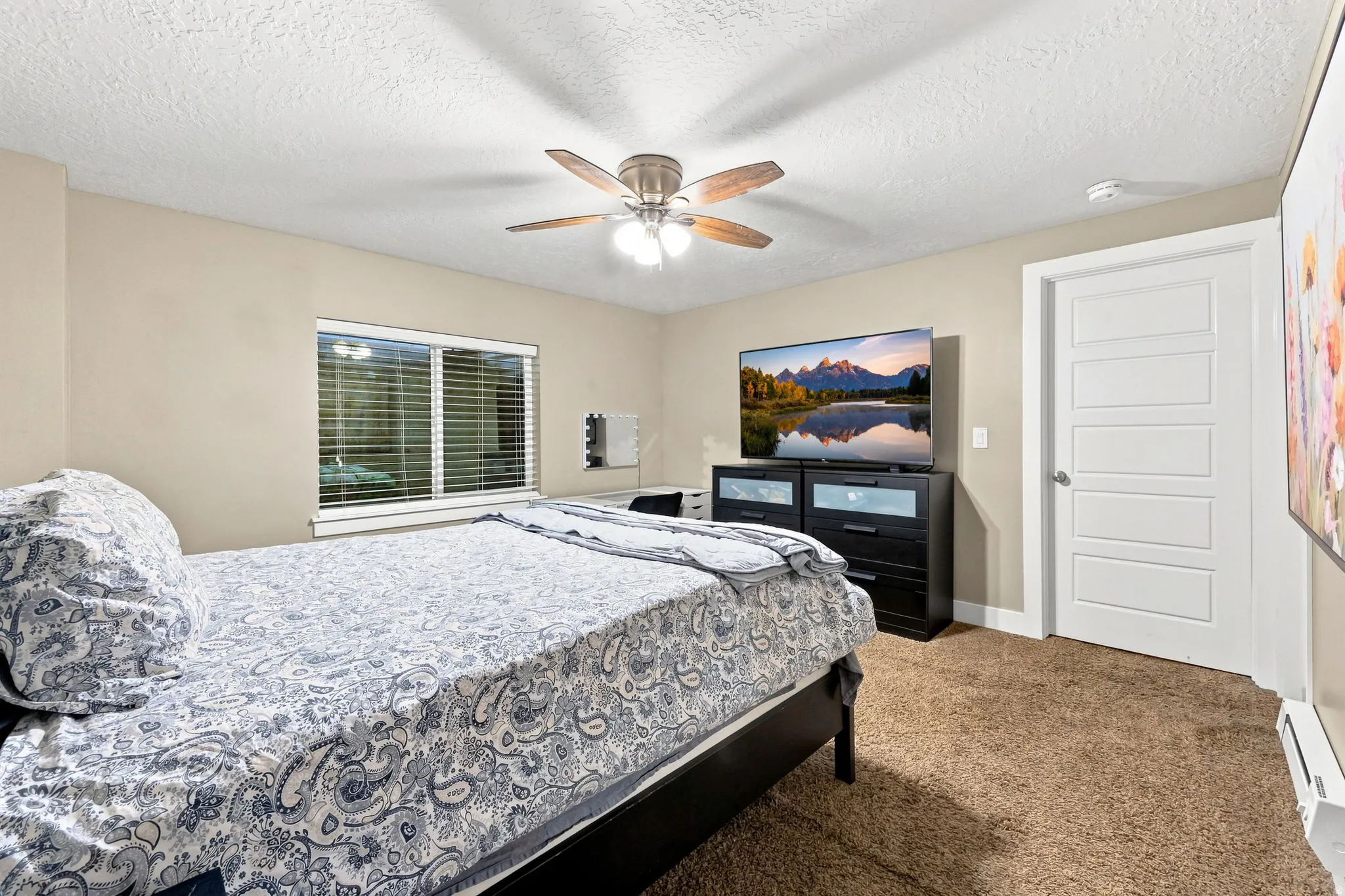 Carpeted room with a ceiling fan, window with blinds, and white panel door