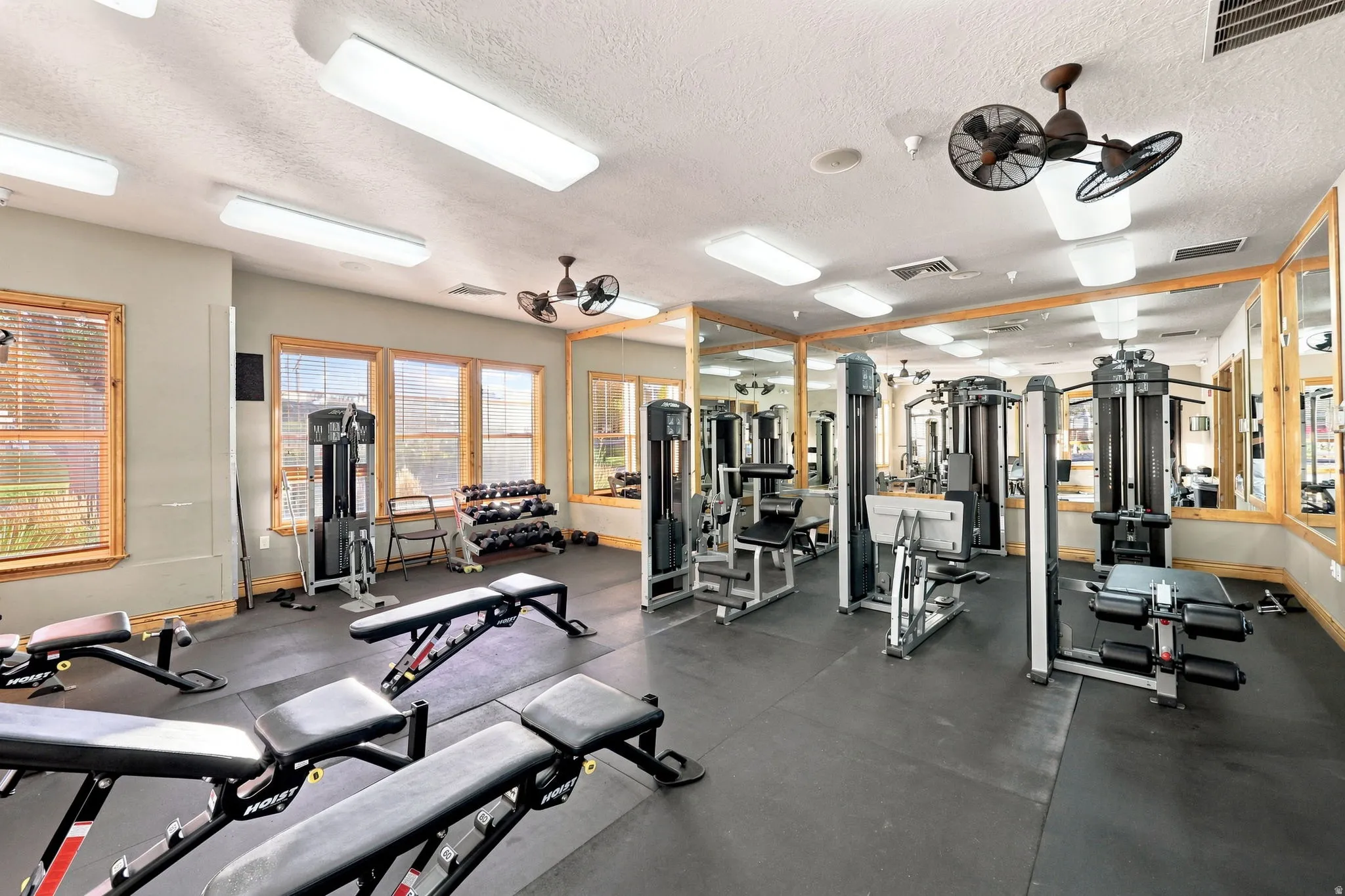 Fitness center with rubber flooring, extensive mirror wall, track lighting, and multiple windows