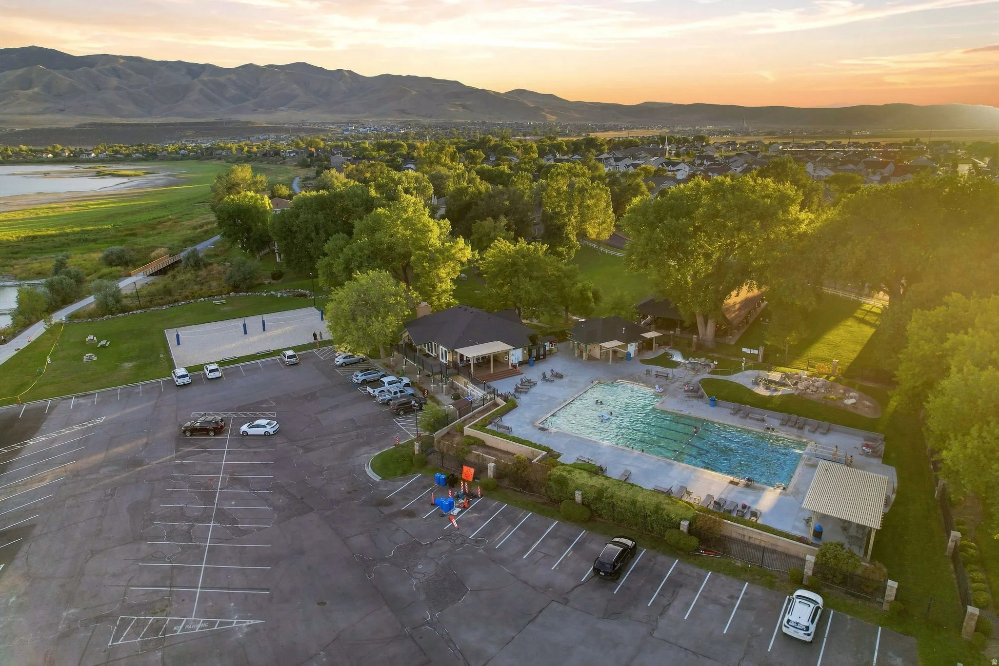 Expansive outdoor pool with multiple swimming lanes, surrounding paved patio, and adjacent clubhouse building