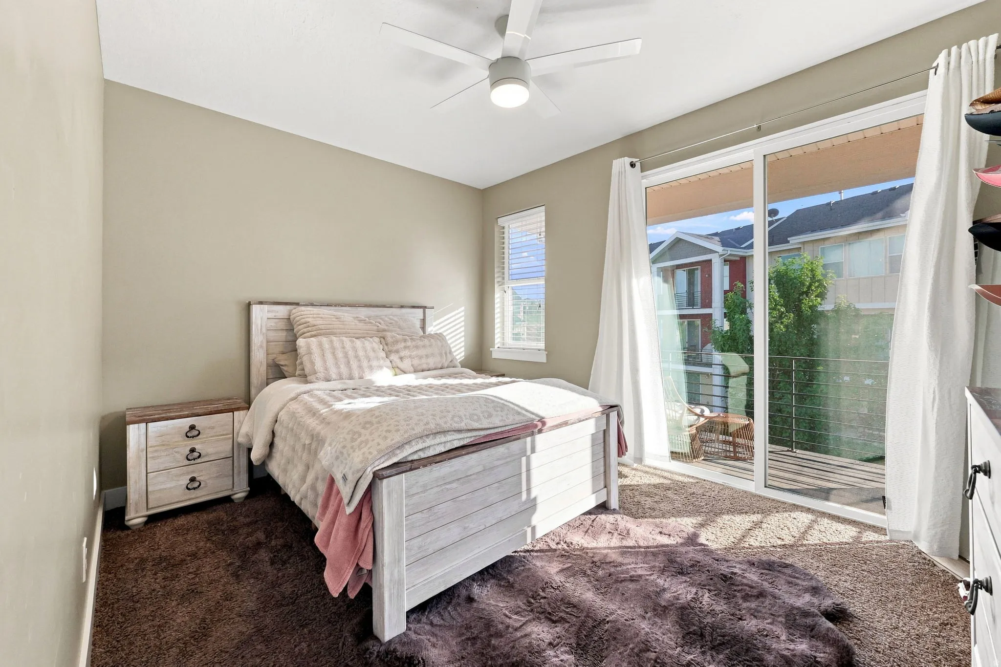 Sliding glass door access to an exterior balcony, modern ceiling fan, single window with blinds, and neutral wall paint