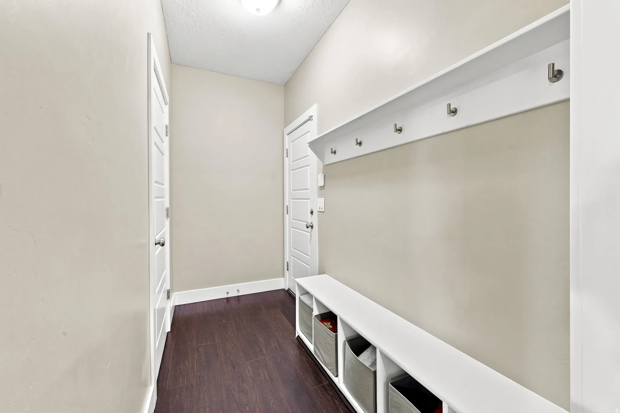 Entryway mudroom with wood-finish flooring, built-in shelving, and coat hooks