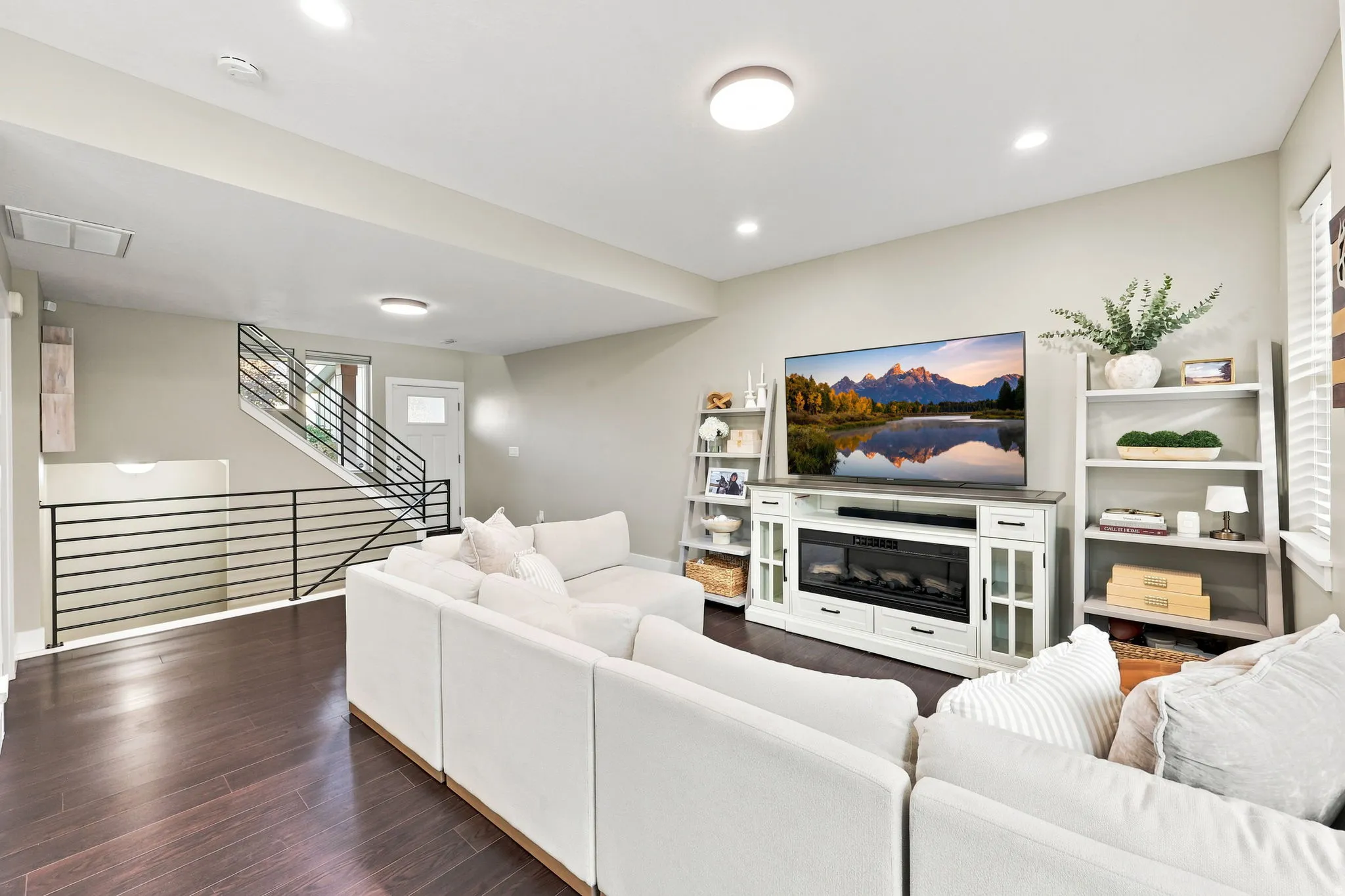 Spacious living area featuring wood-finish flooring, recessed lighting, and modern black horizontal bar railings