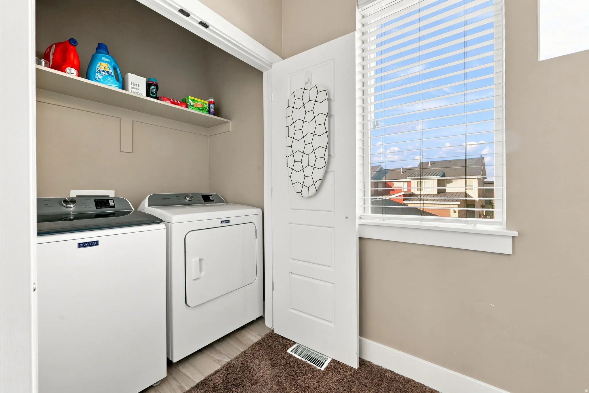 Laundry area featuring a built-in shelf, washer, dryer, and a window with blinds