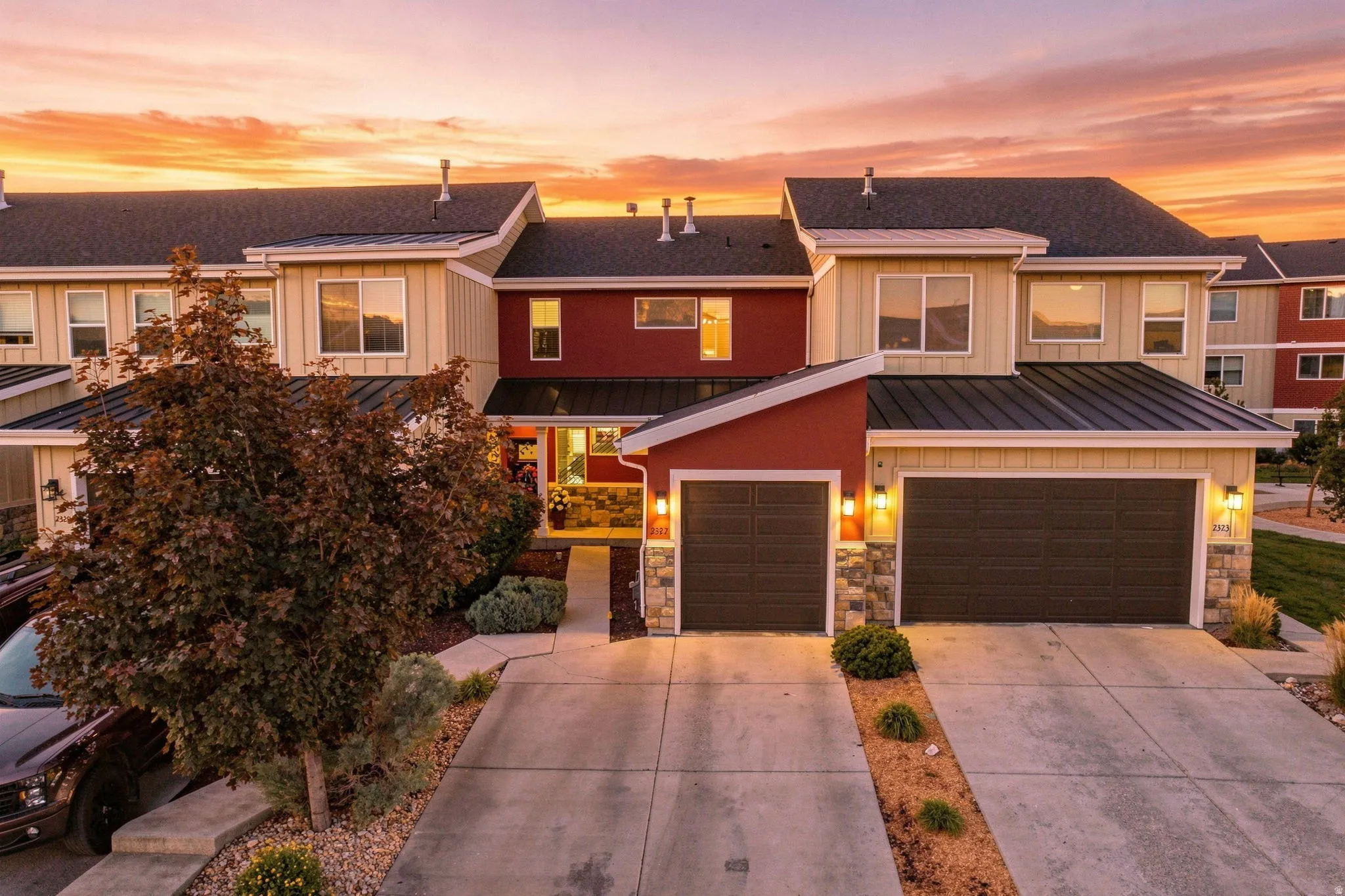 Exterior features stone accents, multiple garage bays, and a metal roof over the entry
