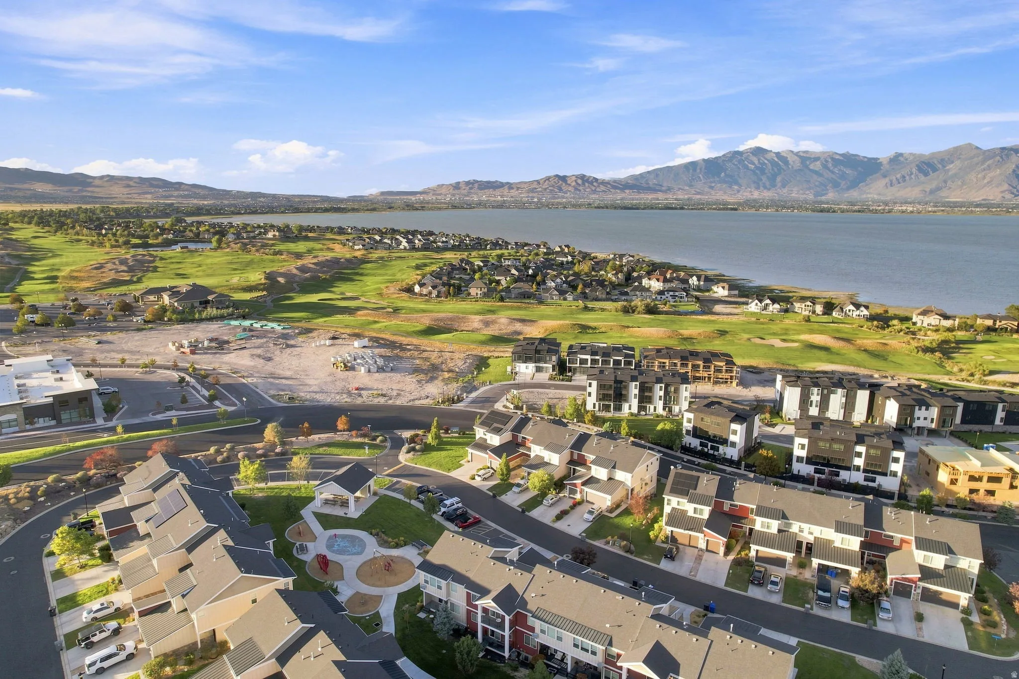 Community featuring residential structures, a prominent body of water, expansive green spaces, and mountainous terrain