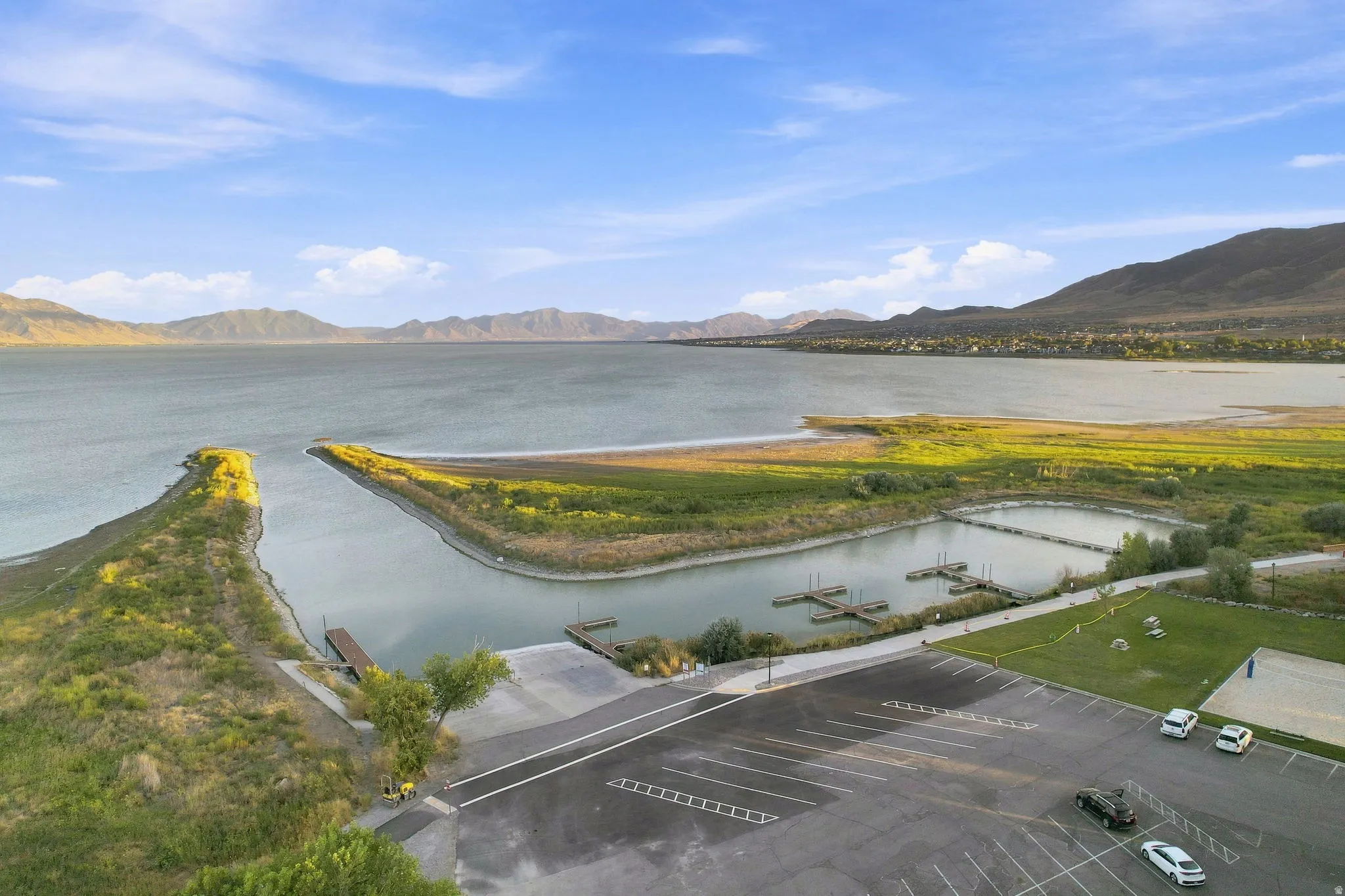 Expansive lake with mountain backdrop, featuring a boat launch, boat slips, and parking area