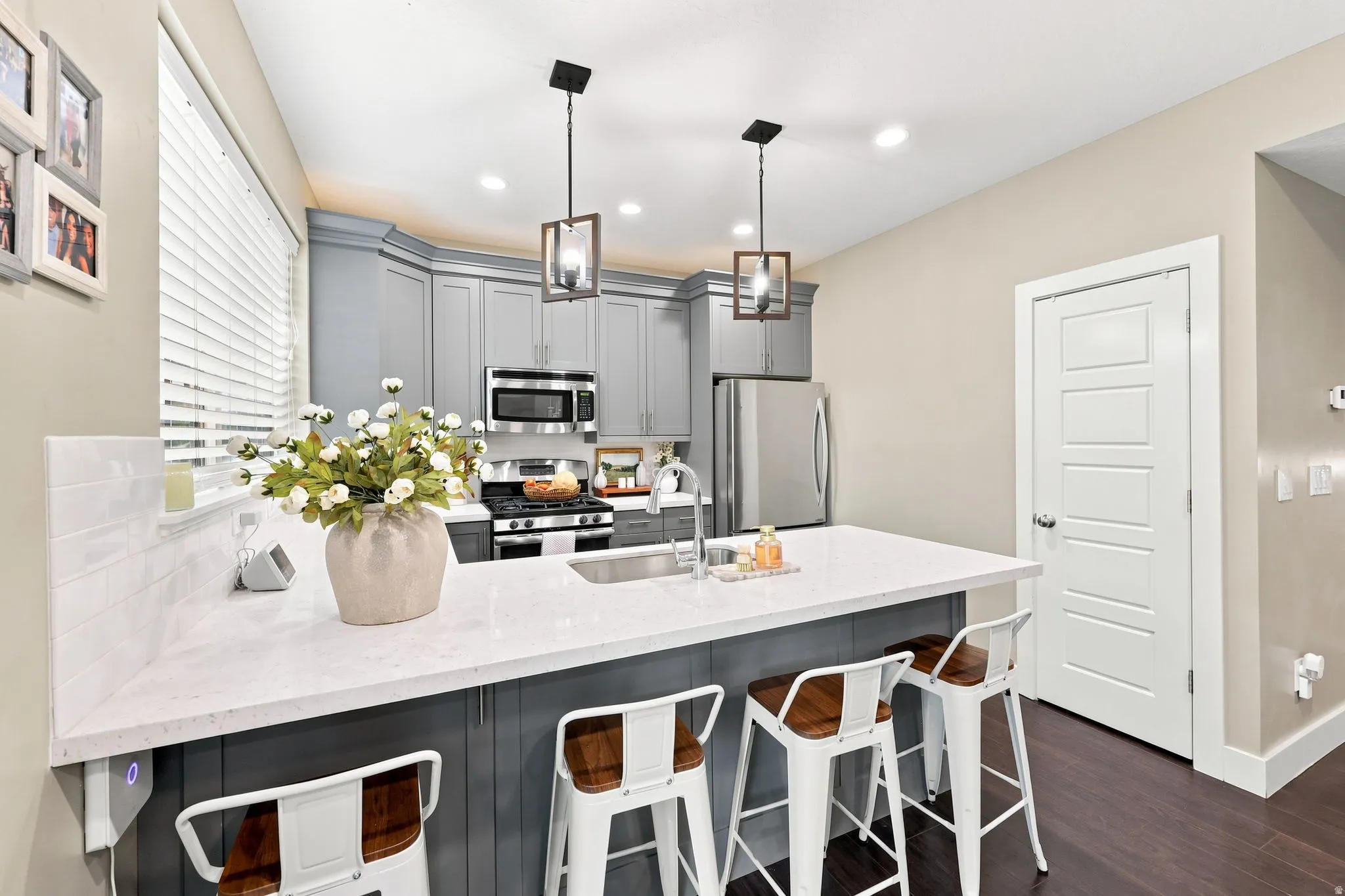 Kitchen featuring a central island with countertop seating, gray cabinetry, stainless steel appliances, and wood-finish flooring