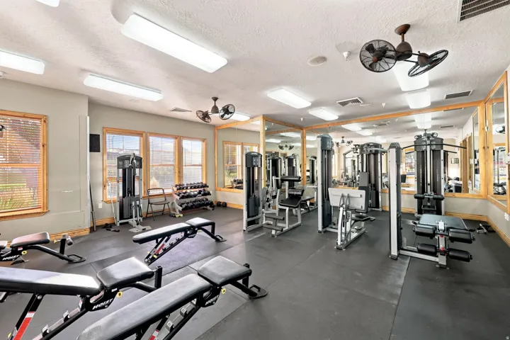 Fitness center with rubber flooring, extensive mirror wall, track lighting, and multiple windows