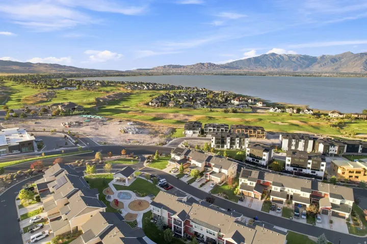 Community featuring residential structures, a prominent body of water, expansive green spaces, and mountainous terrain