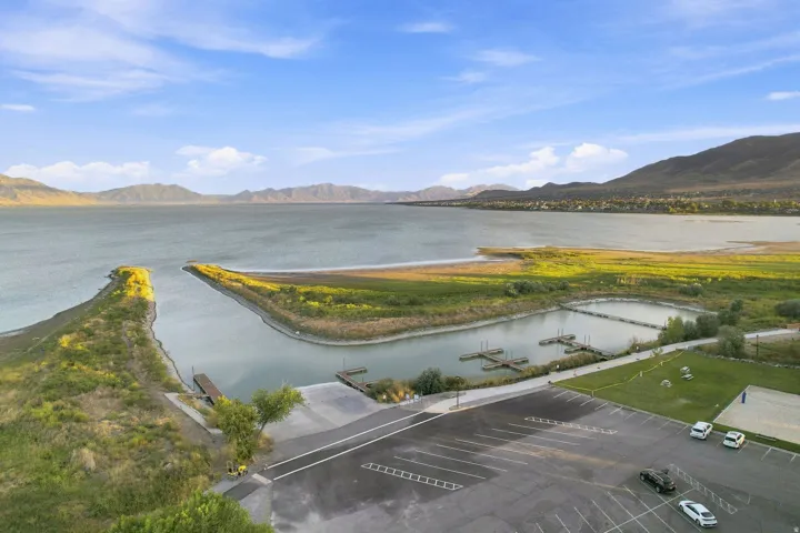 Expansive lake with mountain backdrop, featuring a boat launch, boat slips, and parking area