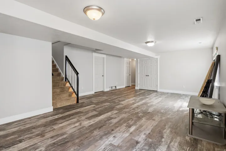 Spacious room featuring wood-finish flooring, light gray walls, and multiple flush-mount lighting fixtures