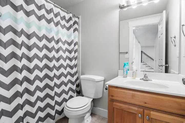 Bathroom featuring a wood-finish vanity with a white countertop and an integrated sink, a large wall mirror, and overhead vanity lighting